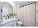 Bright bathroom features a modern black framed mirror, a white sink, and a shower with a white shower curtain at 5800 Elegant Orchid Way, Sarasota, FL 34232