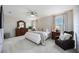 Spacious main bedroom featuring neutral walls, soft carpet, ceiling fan, and large windows bringing in natural light at 5800 Elegant Orchid Way, Sarasota, FL 34232