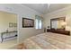 Bedroom featuring a bed, dresser, mirror and a view through a large window, creating a serene retreat at 7005 River Hammock Dr # 402, Bradenton, FL 34212