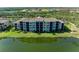 Waterfront condo building with tile roof, well-maintained landscaping, and pristine green lawn at 7005 River Hammock Dr # 402, Bradenton, FL 34212