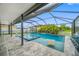 A screened pool and spa with sun shelf are surrounded by stone pavers; with an outdoor kitchen at 7107 58Th E Ter, Palmetto, FL 34221