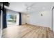 Bright bedroom featuring wood floors, a ceiling fan, shiplap accent wall, and sliding glass door to the outside at 722 N Manasota Key Rd, Englewood, FL 34223