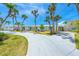 Charming home featuring vibrant yellow double doors, lush green lawn, and a circular driveway at 722 N Manasota Key Rd, Englewood, FL 34223