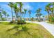 Charming home featuring vibrant yellow double doors, lush green lawn, and palm trees at 722 N Manasota Key Rd, Englewood, FL 34223