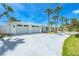 Home featuring a spacious three car garage, a lush green lawn, and palm trees at 722 N Manasota Key Rd, Englewood, FL 34223