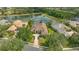Aerial view of home with tile roof, beautiful landscaping, and surrounded by lush greenery and a serene pond view at 7305 Chatsworth Ct, University Park, FL 34201