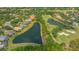 Aerial view of the home with a lake view, surrounded by a golf course and tropical landscaping at 7305 Chatsworth Ct, University Park, FL 34201