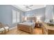 Cozy bedroom with blue walls, light wood floors, plantation shutters, and a comfortable bed at 7305 Chatsworth Ct, University Park, FL 34201