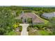 Stunning single-story home featuring tile roof, columns, and a brick driveway surrounded by lush greenery and a serene pond view at 7305 Chatsworth Ct, University Park, FL 34201