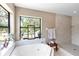 Bright bathroom with a tub, decorative window, stool, and a tiled walk-in shower at 7407 91St E St, Palmetto, FL 34221