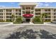 Inviting condo exterior with palm trees and well-maintained landscaping, featuring a covered entrance and ample parking at 7461 W Country Club Dr N # 408, Sarasota, FL 34243