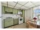 Functional kitchen featuring unique green cabinetry, white appliances, and a cozy dining nook near the window at 7461 W Country Club Dr N # 408, Sarasota, FL 34243