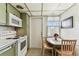Efficient kitchen layout with green cabinets, white appliances, and a compact dining area with natural light at 7461 W Country Club Dr N # 408, Sarasota, FL 34243