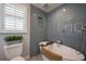 Modern bathroom features sleek gray tile, a walk-in shower, a soaking tub, and a toilet with plants at 750 Tarawitt Dr, Longboat Key, FL 34228