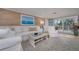 Bright living room features a white sofa, wood-look accent wall and sliding glass doors to the lanai at 750 Tarawitt Dr, Longboat Key, FL 34228