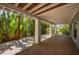 Inviting outdoor patio with brick pavers, lush tropical landscaping, and a covered area for relaxing or entertaining at 750 Tarawitt Dr, Longboat Key, FL 34228