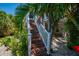 Wooden stairs leading up to the elevated house, surrounded by lush greenery at 750 Tarawitt Dr, Longboat Key, FL 34228