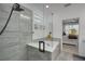 Modern bathroom featuring glass shower, soaking tub, gray tile, and access to bedroom at 7859 Yale Harbor Dr, Wesley Chapel, FL 33545