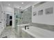 Bright bathroom featuring a glass enclosed shower and soaking tub with gray tiling and modern fixtures at 7859 Yale Harbor Dr, Wesley Chapel, FL 33545