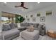 Comfortable living room featuring a spacious sectional sofa, a modern ceiling fan, and backyard views at 7859 Yale Harbor Dr, Wesley Chapel, FL 33545