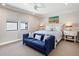 Well-lit bedroom features a cozy blue loveseat, serene decor, and two windows enhancing its inviting feel at 7864 Grande Shores Dr, Sarasota, FL 34240