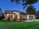 Charming home at dusk boasting lush landscaping, a two-car garage, and a tile roof at 7864 Grande Shores Dr, Sarasota, FL 34240