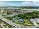 Aerial view of a residential neighborhood with tennis courts and views of a lake in the distance at 8067 Waterbend Trl, Sarasota, FL 34240