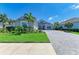 Well-manicured front lawn and gardens with stone driveway and elegant home exterior at 8067 Waterbend Trl, Sarasota, FL 34240