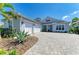 Beautiful gray home showcasing a three-car garage and a meticulously designed paver driveway at 8067 Waterbend Trl, Sarasota, FL 34240