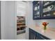 A walk-in pantry with shelving, canned goods, and supplies sits adjacent to the counter area with stylish blue cabinetry at 8067 Waterbend Trl, Sarasota, FL 34240