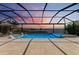 Screened pool with spa and chairs overlooking a scenic sunset over the lake at 8067 Waterbend Trl, Sarasota, FL 34240