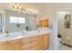 Bright bathroom with double sinks, framed mirrors and natural wood cabinets at 8712 Grey Oaks Ave, Sarasota, FL 34238