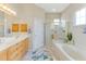 Bright bathroom with a tub, glass shower, and natural wood cabinetry at 8712 Grey Oaks Ave, Sarasota, FL 34238