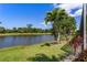 Picturesque view of a serene lake framed by mature trees and colorful landscaping at 8712 Grey Oaks Ave, Sarasota, FL 34238