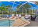 Relaxing screened patio with a pool, lake view, and comfortable seating arrangements at 8712 Grey Oaks Ave, Sarasota, FL 34238