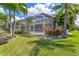 A tranquil screened-in pool surrounded by lush greenery and mature palm trees at 8712 Grey Oaks Ave, Sarasota, FL 34238