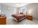 Neutral bedroom with tile flooring, ceiling fan, and a queen sized bed with traditional style furniture at 11895 Claremont Dr, Port Charlotte, FL 33981