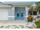 Close up of the front entrance showing blue double doors, well manicured landscaping and a two car garage at 11895 Claremont Dr, Port Charlotte, FL 33981