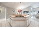 Kitchen island featuring a dual sink, clock, decor, and white cabinets with a view of the dining area at 11895 Claremont Dr, Port Charlotte, FL 33981