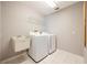 Laundry room with washer, dryer, utility sink, and wire shelf with neutral paint and tile flooring at 11895 Claremont Dr, Port Charlotte, FL 33981