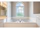 Close up of luxurious soaking tub with arched window in main bathroom at 11895 Claremont Dr, Port Charlotte, FL 33981