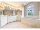 Large main bathroom with dual vanities, soaking tub, and arched window at 11895 Claremont Dr, Port Charlotte, FL 33981