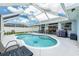 The screened-in pool sits behind a patio with lounge furniture and a grill at 11895 Claremont Dr, Port Charlotte, FL 33981