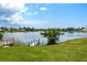 Scenic waterfront view with private dock, lush green lawn, and calm lake reflecting a sunny sky at 11895 Claremont Dr, Port Charlotte, FL 33981