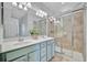 Well-lit bathroom with double sinks, a spacious mirror, and a glass-enclosed shower at 20228 Lagente Cir, Venice, FL 34293