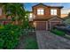 Charming two-story townhome featuring a well-manicured lawn, paver driveway, and attached garage at 20228 Lagente Cir, Venice, FL 34293