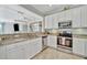 Well-lit kitchen featuring white cabinets, stainless steel appliances, and granite countertops with bar seating at 20228 Lagente Cir, Venice, FL 34293