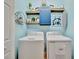 Laundry room with a blue accent wall, open shelves, and washer and dryer at 20228 Lagente Cir, Venice, FL 34293