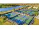 Aerial view of pickleball courts alongside a scenic lake in a beautifully landscaped community at 20228 Lagente Cir, Venice, FL 34293