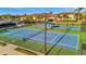 Multiple well-maintained tennis courts with a covered bench area and surrounding landscaping at 20228 Lagente Cir, Venice, FL 34293